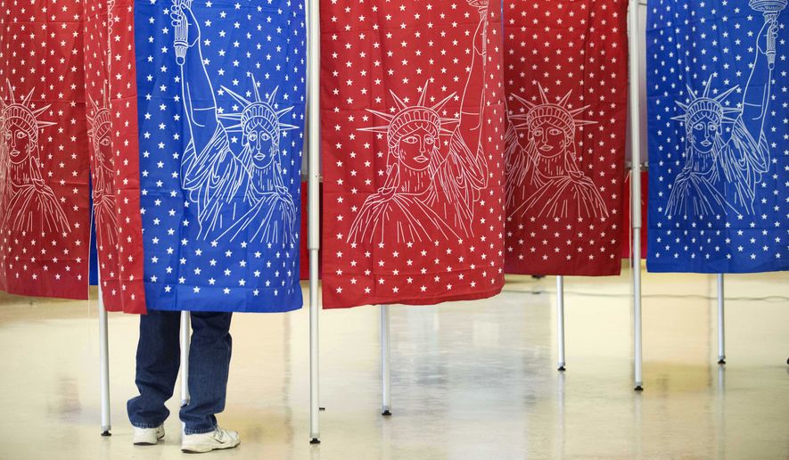 A voter marks a ballot for the New Hampshire primary inside a voting booth at a polling place Tuesday, Feb. 9, 2016, in Manchester, N.H. (AP Photo/David Goldman)