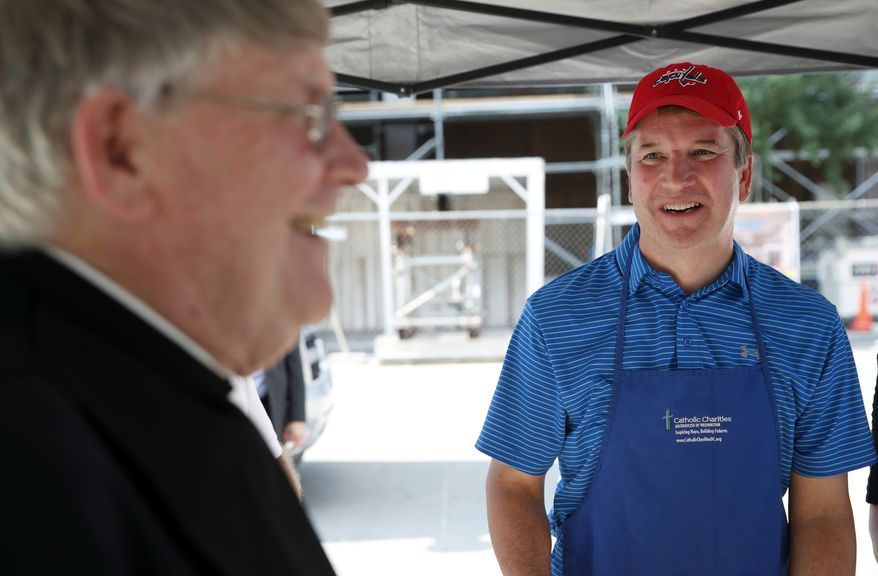 Monsignor John Enzler, left, President and CEO of Catholic Charities, Archdiocese of Washington, talks with Supreme Court nominee Brett Kavanaugh as he serves meals to the homeless as he volunteers with Catholic Charities, Wednesday, July 11, 2018 in Washington. (AP Photo/Alex Brandon)