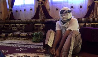 In this May 11, 2017, file photo, a former detainee covers his face for fear of being detained again, as he shows how he was kept in handcuffs and leg shackles while held in a secret prison at Riyan airport in the Yemeni city of Mukalla. In a report released Thursday, July 12, 2018, Amnesty International called for an investigation into alleged disappearances, torture and likely deaths in detention facilities in southern Yemen as possible war crimes.  (AP Photo/Maad El Zikry, File)