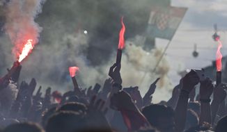Supporters of the Croatian national soccer team light flares and cheer their team on as they watch the World Cup final soccer game on a screen in central Zagreb, Croatia, Sunday, July 15, 2018. Croatia&#39;s national soccer team lost to France in the World Cup final in Russia. (AP Photo/Marko Drobnjakovic)