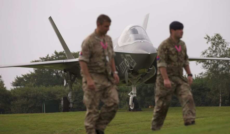 British military soldiers walk past a scale model of a F35 jet forming part of an exhibit on the grounds of the Celtic Manor Resort prior to a NATO summit in Newport, Wales on Wednesday, Sept. 3, 2014. NATO heads of state meet for a two-day summit beginning on Thursday. (AP Photo/Jon Super)