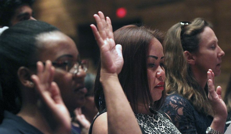 In this file photo, future citizens raise their hands in an oath during the U.S. District Court District of Wyoming naturalization ceremony Monday, July 16, 2018, at the Cheyenne Civic Center. Fifteen citizens from 13 countries were naturalized. (Jacob Byk/The Wyoming Tribune Eagle via AP) **FILE**