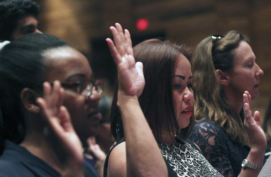 In this file photo, future citizens raise their hands in an oath during the U.S. District Court District of Wyoming naturalization ceremony Monday, July 16, 2018, at the Cheyenne Civic Center. Fifteen citizens from 13 countries were naturalized. (Jacob Byk/The Wyoming Tribune Eagle via AP) **FILE**