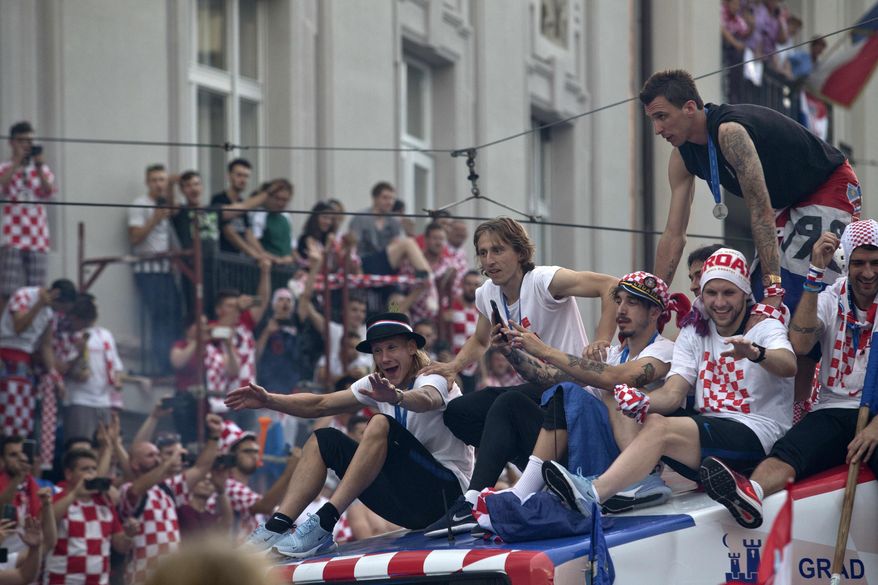 Croatia&#39;s national soccer team members are seen on top of an open bus as they are greeted by fans during a celebration in central Zagreb, Croatia, Monday, July 16, 2018. In an outburst of national pride and joy, Croatia rolled out a red carpet and staged a euphoric heroes&#39; welcome for the national team on Monday despite its loss to France in the World Cup final. (AP Photo/Marko Drobnjakovic)
