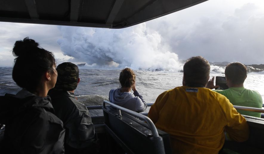 FILE - In this May 20, 2018 file photo, people watch a plume of steam as lava enters the ocean near Pahoa, Hawaii. Officials say an explosion sent lava flying through the roof of a tour boat off the Big Island, Monday, July 16, 2018, injuring at least 13 people. The people were aboard a tour boat that takes visitors to see lava from an erupting volcano plunge into the ocean. (AP Photo/Jae C. Hong, File)