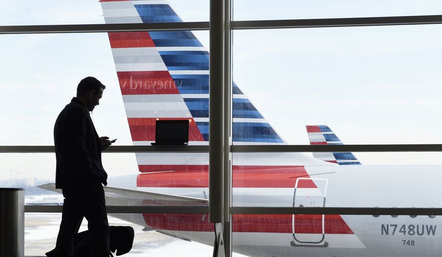 FILE - In this Jan. 25, 2016, file photo, a passenger talks on the phone as American Airlines jets sit parked at their gates at Washington&#x27;s Ronald Reagan National Airport. American Airlines is giving more details on changes that will reward the highest-paying passengers, not just those who fly the most miles, announcing Monday, June 6, 2016, that beginning on Aug. 1, passengers will earn points based on the price of their ticket. Elite-status members of the AAdvantage loyalty program will earn even more points per dollar spent. (AP Photo/Susan Walsh, File)