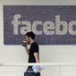 In this March 15, 2013, file photo, a Facebook employee walks past a sign at Facebook headquarters in Menlo Park, Calif. The San Jose Mercury News reports Saturday, March 17, 2018 that building permits compiled by Buildzoom show Facebook plans to erect the 465,000 square-foot (43,200 square-meter) building at its campus in Menlo Park, Calif. (AP Photo/Jeff Chiu, File)
