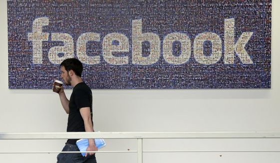 In this March 15, 2013, file photo, a Facebook employee walks past a sign at Facebook headquarters in Menlo Park, Calif. The San Jose Mercury News reports Saturday, March 17, 2018 that building permits compiled by Buildzoom show Facebook plans to erect the 465,000 square-foot (43,200 square-meter) building at its campus in Menlo Park, Calif. (AP Photo/Jeff Chiu, File)
