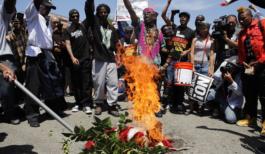 People chant slogans as they burn a U.S. flag outside the Los Angeles office of U.S. Rep. Maxine Waters, Thursday, July 19, 2018, in Los Angeles. A crowd gathered at the field office to counter a protest by a self-styled militia group burned the flag taken from the back of a pickup truck that drove up to the scene. (AP Photo/Jae C. Hong)