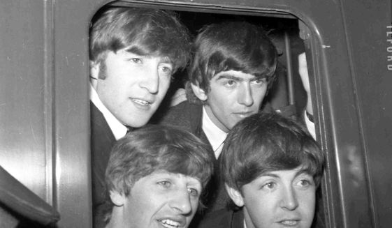 In this March 2, 1964 file photo, Britain&#39;s pop group The Beatles, from top left John Lennon, George Harrison and from bottom left, Ringo Starr and Paul McCartney pose in the window of train at Paddington Station in London. (AP Photo/Bob Dear, File)