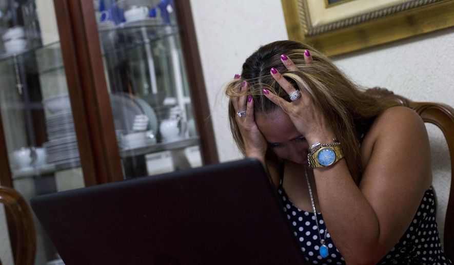ADVANCE FOR USE MONDAY, JULY 23, 2018 AND THEREAFTER-Letty Stegall is overwhelmed by emotion after talking to her daughter and watching the security cameras at the bar she manages back in Kansas City, Mo., as she sits at a table in her parents' home in Boca Del Rio, Veracruz state, Mexico on Thursday, May 24, 2018. Stegall, who is married to an American and has an American daughter, was deported to Mexico in March. “I wish I was there. That’s all that I want,” she says of her life in the U.S. “I want my family back.” (AP Photo/Rebecca Blackwell)