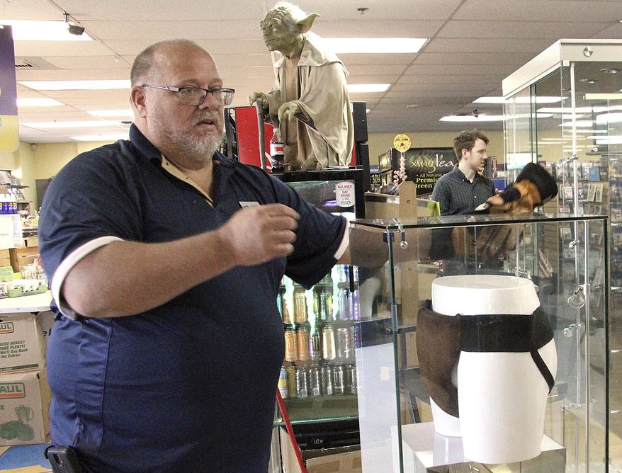 FILE - In this May 2, 2018 file photo, Blockbuster Alaska general manager Kevin Daymude moves a display case featuring the jockstrap worn by actor Russell Crowe in the 2005 movie "Cinderella Man" at a Blockbuster video store in Anchorage, Alaska. Everything in the closing Blockbuster video store in Alaska is for sale, except the celebrity jockstrap. (AP Photo/Mark Thiessen, File)