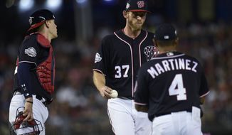 Washington Nationals starting pitcher Stephen Strasburg (37) hands the ball to manager Dave Martinez, (4) as he is pulled from a baseball game as catcher Jamie Burke, left, watches during the fifth inning against the Atlanta Braves at Nationals Park in Washington, Friday, July 20, 2018. (AP Photo/Susan Walsh)