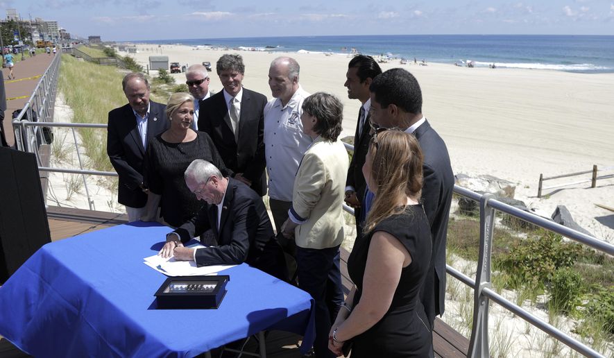 Lawmakers stand by as New Jersey Gov. Phil Murphy, center, signs a bill banning smoking on parks and beaches on the boardwalk in Long Branch, N.J., Friday, July 20, 2018. Fines would start at $250 for a first offense and go up to $1,000 for a third offense for people smoking out of designated areas. (AP Photo/Julio Cortez)