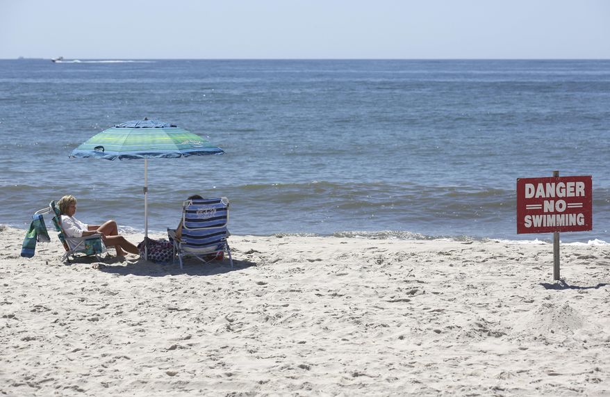 A "no swimming" sign is seen near Ocean Beach on Fire Island in Islip, N.Y., Thursday, July 19, 2018. Two children were bitten in the leg in the waters off New York's Fire Island on Wednesday in possible shark attacks, prompting beach closings, authorities said.(AP Photo/Seth Wenig)