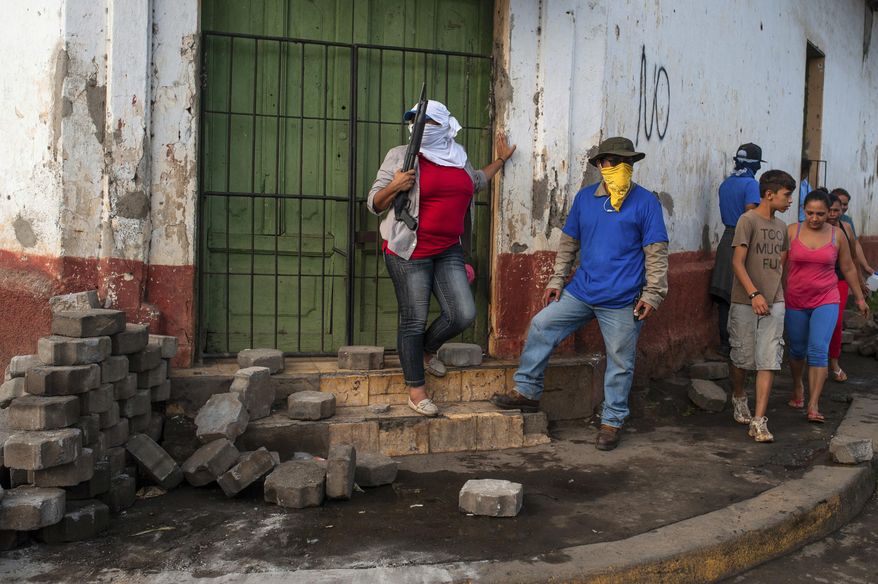 In this Tuesday, July 17, 2018 photo, Sandinista militias stand guard at a dismantled barricade after police and pro-government militias stormed the Monimbo neighborhood of Masaya, Nicaragua. Heavily armed police and militias laid siege to and then retook the symbolically important neighborhood that had recently become a center of resistance to President Daniel Ortega's government. (AP Photo/Cristobal Venegas)
