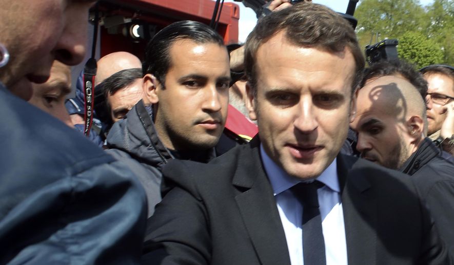 FILE - In this Wednesday April 26, 2017 file photo, Emmanuel Macron, right, is flanked by his bodyguard, Alexandre Benalla, left background, outside the Whirlpool home appliance factory, in Amiens, northern France. Investigators have detained for questioning on Friday, July 20, 2018 one of President Emmanuel Macron&#x27;s top security aides caught on camera beating a protester in May, a turn of events now evolving into a major political crisis for the president. The presidential Elysee Palace said it is taking steps to fire Alexandre Benalla, who was identified earlier this week by the newspaper Le Monde for beating a young protester during May Day protests while wearing a police helmet (AP Photo/Thibault Camus, File)