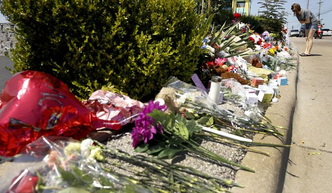 A woman looks at a memorial in front of Ride the Ducks Saturday, July 21, 2018 in Branson, Mo. One of the company's duck boats capsized Thursday night resulting in several deaths on Table Rock Lake. (AP Photo/Charlie Riedel)