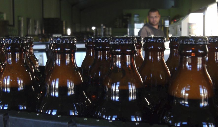 In this June 5, 2018, photo, bottles of freshly bottled beer stand in the Darling Brewery in Darling, South Africa. The South African brewery appears to be the first in Africa to go carbon-neutral as more businesses across the continent adjust to climate change, and as consumers become more careful about the products they buy. (AP Photo/Neil Shaw)