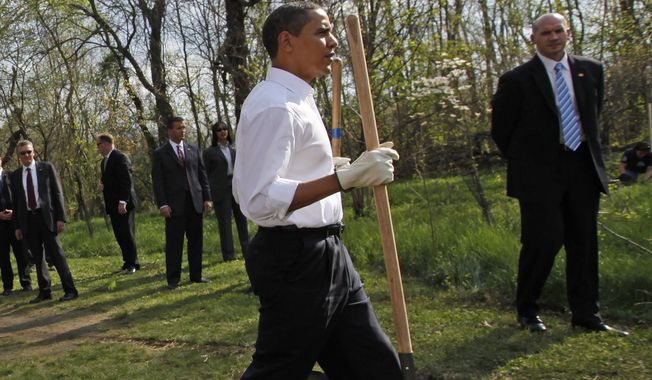 U.S. Secret Service agents stand watch as President Barack Obama walks with two shovels as he gets ready to plant a tree while participating in a national service project at Kenilworth Aquatic Garden in Washington, Tuesday, April 21, 2009. (AP Photo/Charles Dharapak)