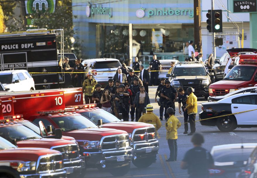 Los Angeles Police SWAT officers escort a group of Trader Joe&#39;s supermarket employees, after a gunman had barricaded himself inside the store in Los Angeles Saturday, July 21, 2018. Police believe a man involved in a standoff at the Los Angeles supermarket shot his grandmother and girlfriend and then fired at officers during a pursuit before he crashed into a utility pole outside the supermarket and ran inside the store. (AP Photo/Damian Dovarganes)