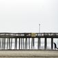 A man walks against a stiff wind under the Jolly Roger Amusement Pier in Ocean City, Md., Saturday, Oct. 3, 2015. Rainfall and heavy winds are expected to last through the weekend. (AP Photo/Cliff Owen) ** FILE **
