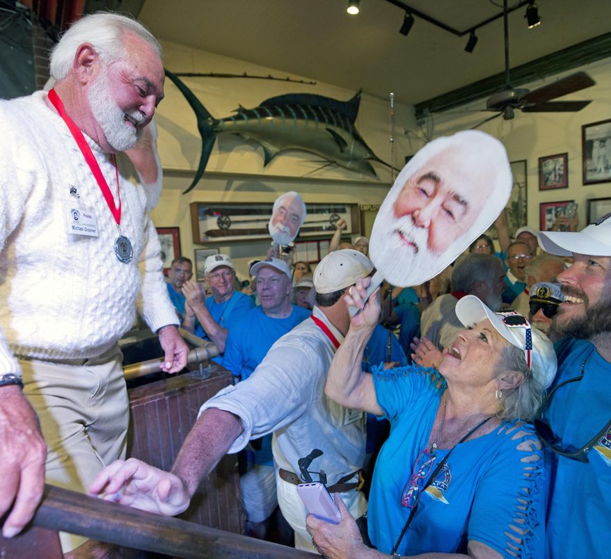 In this Saturday, July 21, 2018, photo provided by the Florida Keys News Bureau, Michael Groover, left, husband of celebrity chef Paula Deen, right, walks off the stage after competing in the semi-final round of the Hemingway Look-Alike Contest at Sloppy Joe's Bar in Key West, Fla. On his ninth attempt, Groover won the competition, the highlight event of the island city's annual Hemingway Days festival that ends Sunday, July 22. (Andy Newman/Florida Keys News Bureau via AP)