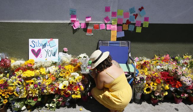 A makeshift memorial of flowers, candles and notes grows on the sidewalk outside the Los Feliz Trader Joe&#x27;s store in Los Angeles, Sunday, July 22, 2018. A day earlier, Trader Joe&#x27;s employee Melyda Corado was shot and killed at the store by a suspect being chased by police. (AP Photo/Damian Dovarganes)