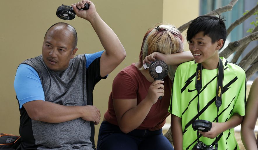 Tourists try to cool off outside the ancient Acropolis hill in Athens, Monday, July 23, 2018. Greece's foremost tourist attraction, the ancient Acropolis in Athens, is closed to visitors at midday due to forecast high temperatures. (AP Photo/Thanassis Stavrakis)