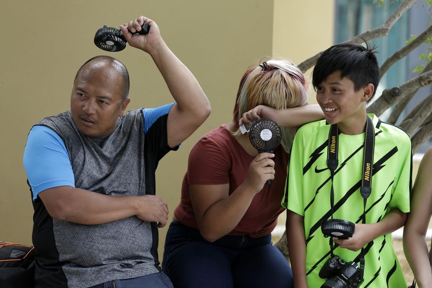 Tourists try to cool off outside the ancient Acropolis hill in Athens, Monday, July 23, 2018. Greece's foremost tourist attraction, the ancient Acropolis in Athens, is closed to visitors at midday due to forecast high temperatures. (AP Photo/Thanassis Stavrakis)
