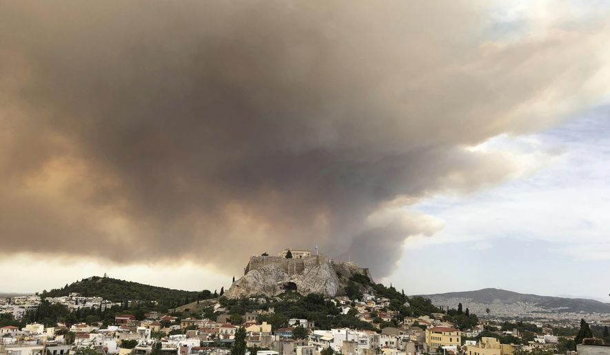 A pall of smoke turns large parts of the sky orange, with the ancient Acropolis hill at centre, as a forest fire burns in a mountainous area west of Athens, sending nearby residents fleeing, Monday, July 23, 2018. The fire department said five water-dropping planes and two helicopters were battling the blaze Monday in the Geraneia mountains near the seaside settlement of Kineta between Athens and Corinth, along with 30 firetrucks and 70 firefighters. (AP Photo/Theodora Tongas)