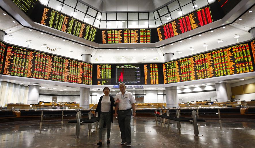 Investors walk in front of trading boards at a private stock market gallery in Kuala Lumpur, Tuesday, July 24, 2018. Asian markets rose on Tuesday as better-than-expected U.S. corporate earnings and the lack of bad news on trade tensions encouraged investors. (AP Photo/Vincent Thian)