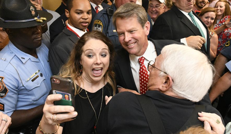 Georgia Republican gubernatorial candidate Brian Kemp, center, stops for a selfie with someone as he makes his way through a crowd of supporters after giving a victory speech during an election night party, Tuesday, July 24, 2018, in Athens, Ga. (AP Photo/John Amis)
