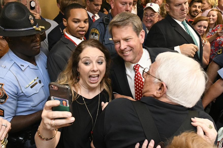 Georgia Republican gubernatorial candidate Brian Kemp, center, stops for a selfie with someone as he makes his way through a crowd of supporters after giving a victory speech during an election night party, Tuesday, July 24, 2018, in Athens, Ga. (AP Photo/John Amis)