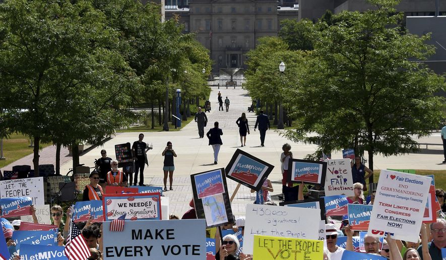 With the Capitol rotunda in the background, demonstrators rally outside the Michigan Hall of Justice in Lansing, Mich., on Wednesday, July 18, 2018, where the Michigan Supreme Court heard arguments about whether voters in November should be able to pass a constitutional amendment that would change how the state’s voting maps are drawn or whether such changes could only be adopted at a rarely held constitutional convention. (Dale G. Young/Detroit News via AP)