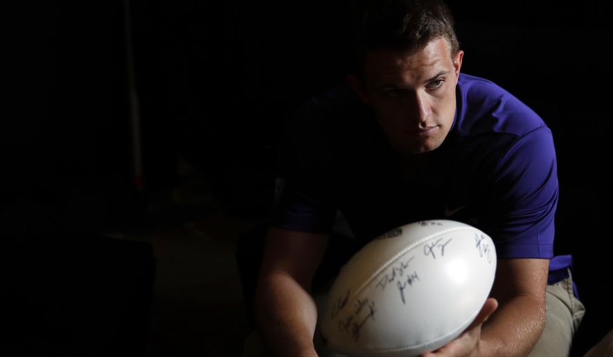 Washington quarterback Jake Browning hands the ball to head coach Chris Petersen, not pictured, in a holding room at the Pac-12 Conference NCAA college football media day in Los Angeles, Wednesday, July 25, 2018. (AP Photo/Jae C. Hong)