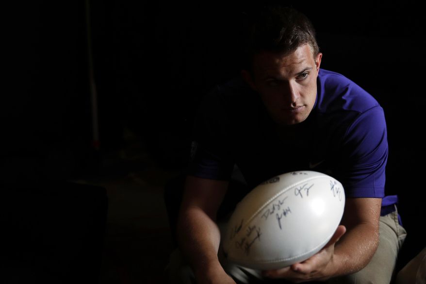 Washington quarterback Jake Browning hands the ball to head coach Chris Petersen, not pictured, in a holding room at the Pac-12 Conference NCAA college football media day in Los Angeles, Wednesday, July 25, 2018. (AP Photo/Jae C. Hong)
