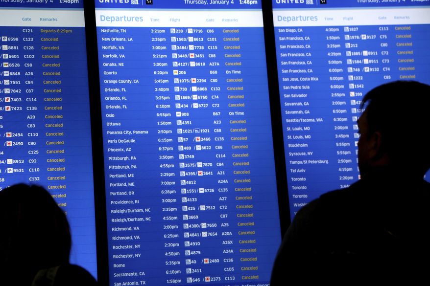 FILE - In this Jan. 4, 2018, file photo, people look at a display that shows mostly cancelled flights at Newark Liberty International Airport in Newark, N.J. If a trip is interrupted by unforeseen emergencies like weather, travel insurance may cover your losses as well as expenses incurred because of the disruption, like rebooking fees for flights or a hotel because you are stranded. (AP Photo/Seth Wenig, File)