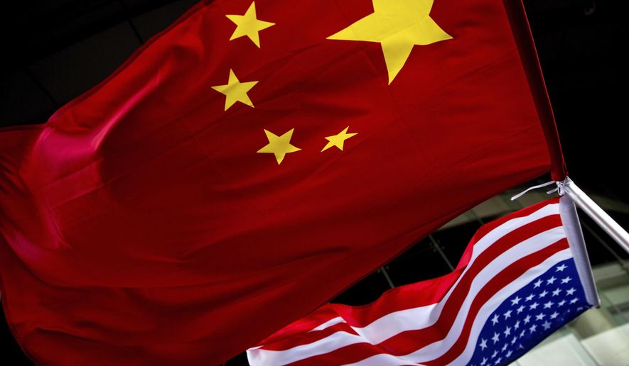 U.S. and Chinese national flags are hung outside a hotel during the U.S. Presidential election event, organized by the U.S. embassy in Beijing. A government report is outlining how spy services from China, Russia and Iran are hard at work trying to steal trade secrets and proprietary information from U.S. companies, government labs and universities. (AP Photo/Andy Wong, File)