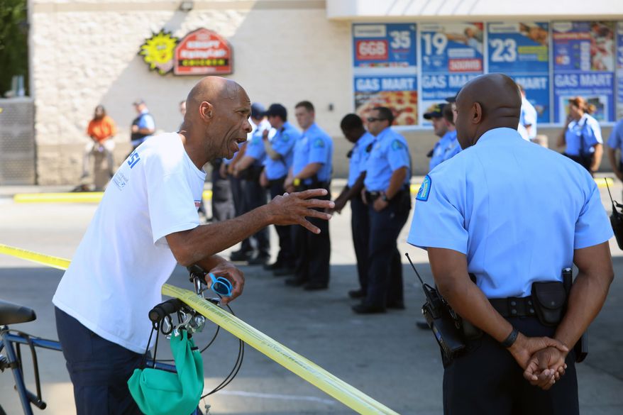 A neighborhood man talks with police who lined up around a Gas Mart at 5745 Delmar Boulevard, Thursday, July 26, 2018 in St. Louis, Mo. The gas station has been the scene of protests after a woman was kicked by two workers from the gas station. andals have damaged a St. Louis gas station where a black woman was allegedly kicked by employees during an altercation caught on video. Police say the Gas Mart store was ransacked Wednesday night, and that a nearby car was set on fire. No injuries have been reported, and no arrests have been made. (Christian Gooden/St. Louis Post-Dispatch via AP)