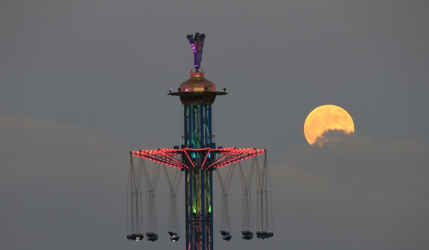 A blood moon rises over Tel Aviv, Israel, Friday, July 27, 2018. Skywatchers around much of the world are looking forward to a complete lunar eclipse that will be the longest this century. The so-called “blood moon” Friday, when it turns a deep red, will be visible at different times in Australia, Africa, Asia, Europe and South America when the sun, Earth and moon line up perfectly, casting Earth’s shadow on the moon. (AP Photo/Ariel Schalit)