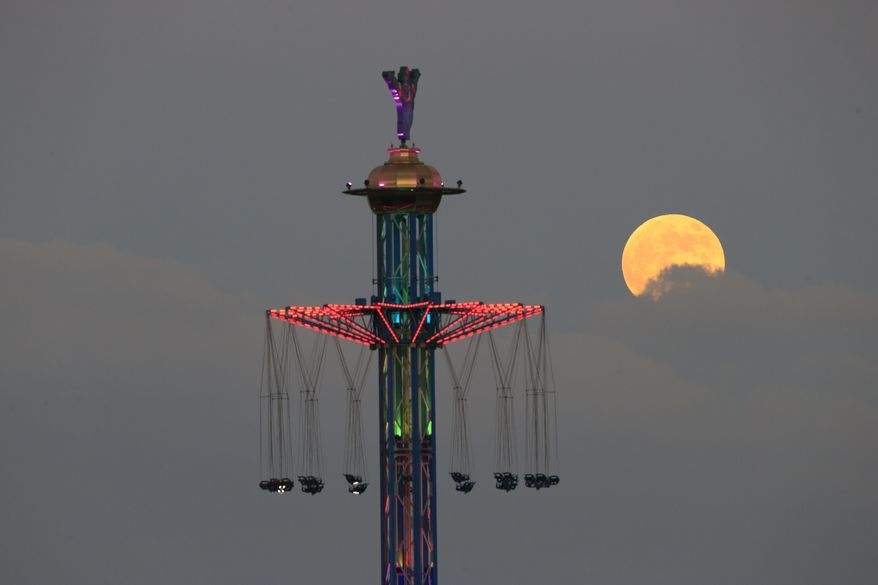 A blood moon rises over Tel Aviv, Israel, Friday, July 27, 2018. Skywatchers around much of the world are looking forward to a complete lunar eclipse that will be the longest this century. The so-called “blood moon” Friday, when it turns a deep red, will be visible at different times in Australia, Africa, Asia, Europe and South America when the sun, Earth and moon line up perfectly, casting Earth’s shadow on the moon. (AP Photo/Ariel Schalit)