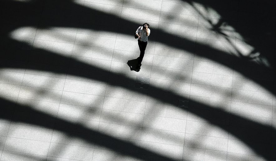 In this Friday, July 20, 2018, photoA man walks in shade of a building in Tokyo. A deadly heat wave in Japan has many residents in the Japanese capital questioning the wisdom of staging the Tokyo 2020 Olympics in July and August. (AP Photo/Eugene Hoshiko, File)