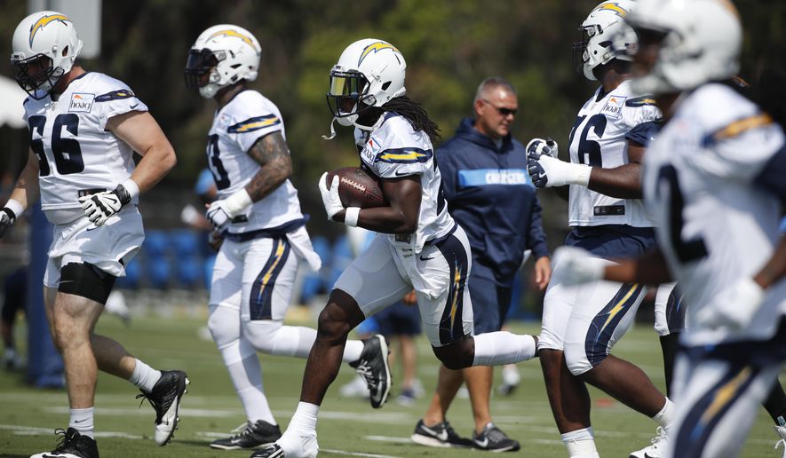 Los Angeles Chargers running back Melvin Gordon, center, carries the ball during NFL football practice, Saturday, July 28, 2018, in Costa Mesa, Calif. (AP Photo/Jae C. Hong)