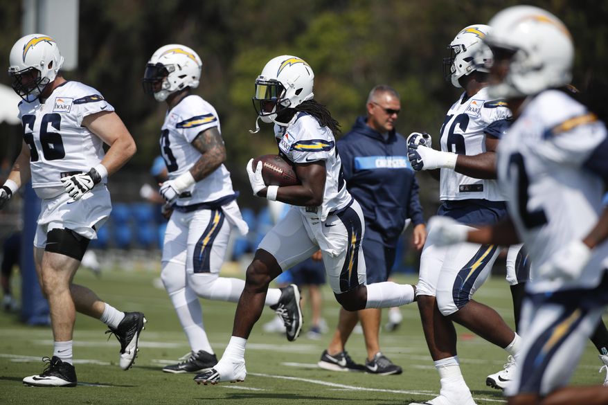 Los Angeles Chargers running back Melvin Gordon, center, carries the ball during NFL football practice, Saturday, July 28, 2018, in Costa Mesa, Calif. (AP Photo/Jae C. Hong)