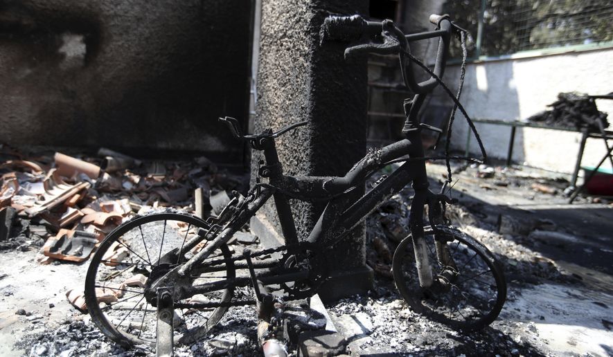 In this Wednesday, July 25, 2018 photo, a burnt bicycle with training wheels stands at the balcony of a destroyed house in Mati, east of Athens. More than 86 people were either killed by the flames or drowned on Monday's wildfire as they tried to flee the fire into the nearby sea, waiting for hours in the water for rescue from local fishermen and private boat owners who saved many. (AP Photo/Thanassis Stavrakis)