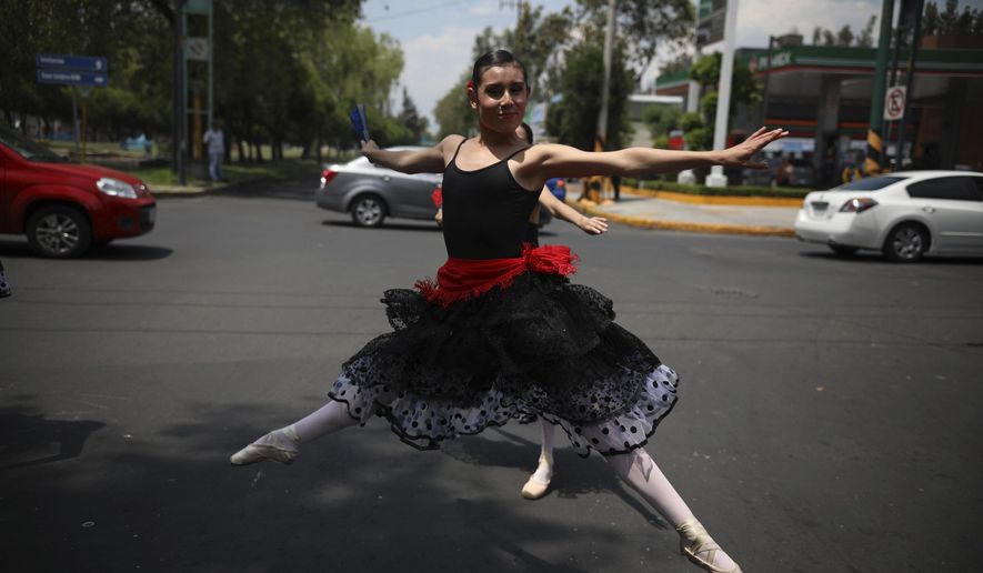 A ballerina dances at a traffic light stop, in Mexico City, Saturday, July 28, 2018. In this sprawling megalopolis notorious for its clogged streets, a theater company sent out tutu-clad dancers out to delight motorists at snarled intersections with snippets from ballet classics like The Nutcracker and Swan Lake all in the 58 seconds it takes for the light to go from red to green. (AP Photo/Emilio Espejel)