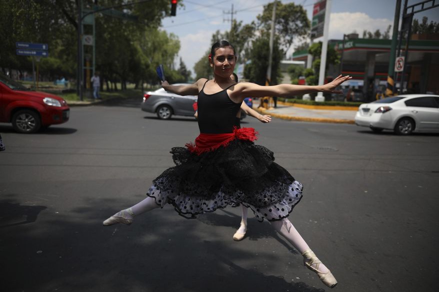 A ballerina dances at a traffic light stop, in Mexico City, Saturday, July 28, 2018. In this sprawling megalopolis notorious for its clogged streets, a theater company sent out tutu-clad dancers out to delight motorists at snarled intersections with snippets from ballet classics like The Nutcracker and Swan Lake all in the 58 seconds it takes for the light to go from red to green. (AP Photo/Emilio Espejel)