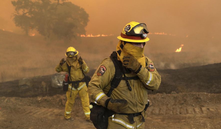 Firefighters with Cal Fire Mendocino Unit cover themselves from smoke and ash created by an advancing wildfire Monday, July 30, 2018, in Lakeport, Calif. A pair of wildfires that prompted evacuation orders for thousands of people are barreling toward small lake towns in Northern California. (AP Photo/Marcio Jose Sanchez)
