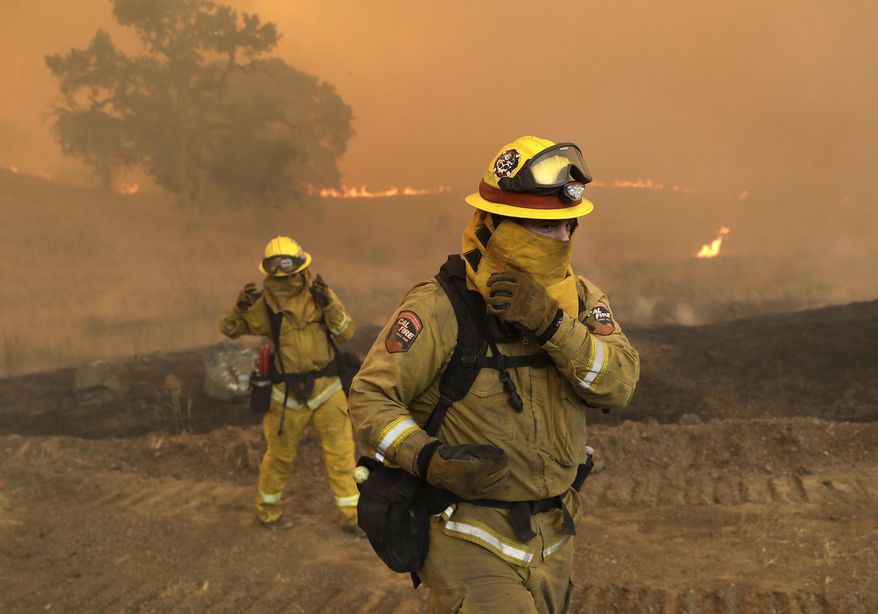 Firefighters with Cal Fire Mendocino Unit cover themselves from smoke and ash created by an advancing wildfire Monday, July 30, 2018, in Lakeport, Calif. A pair of wildfires that prompted evacuation orders for thousands of people are barreling toward small lake towns in Northern California. (AP Photo/Marcio Jose Sanchez)